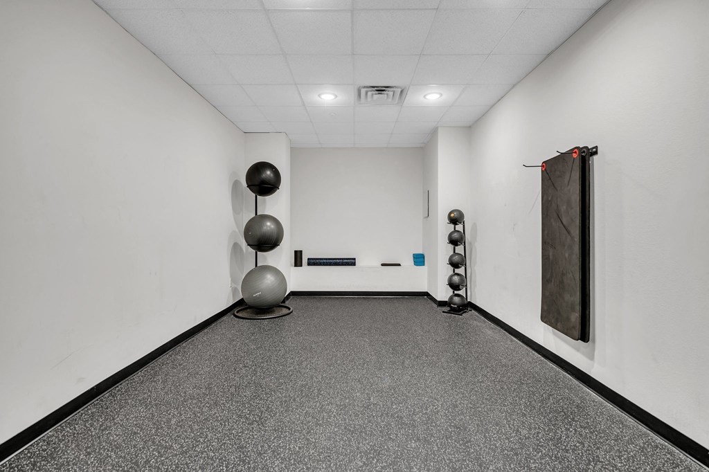 A room with a grey floor and a white wall with a black curtain on the right side.