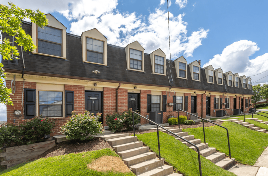 A row of houses with black shutters and white windows.