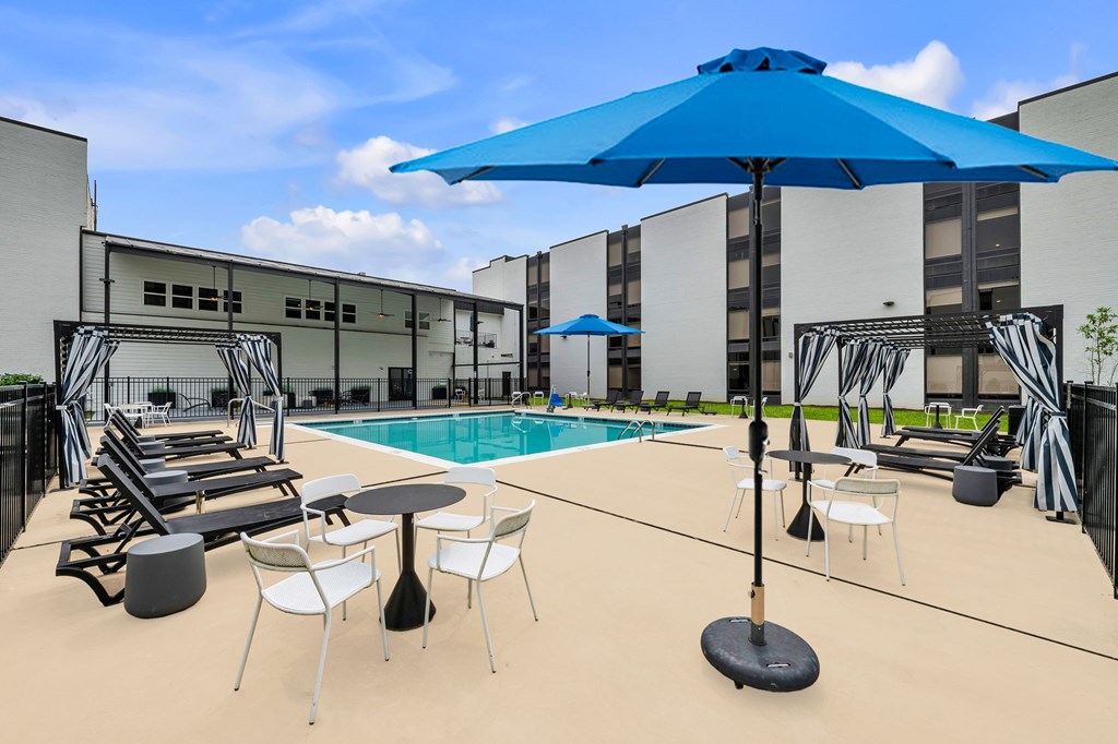 A blue umbrella is in the middle of a table and chairs.