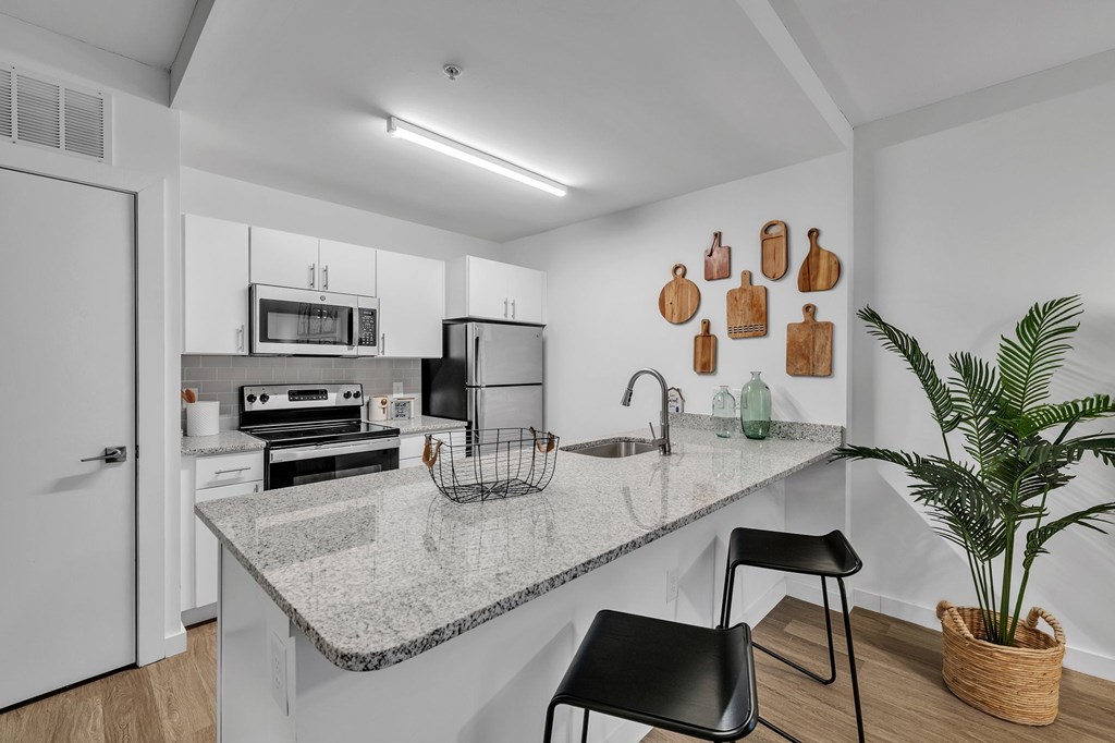 A kitchen with a granite countertop and black chairs.