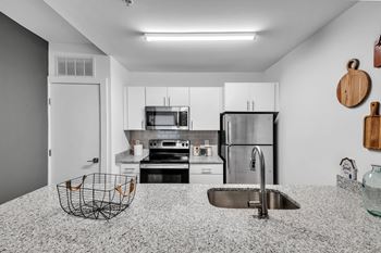 A modern kitchen with a stainless steel refrigerator, microwave, and oven.