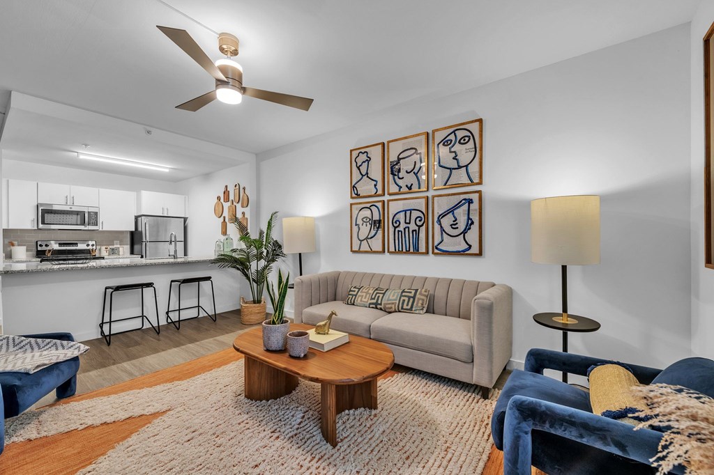A living room with a couch, a coffee table, and a fan.