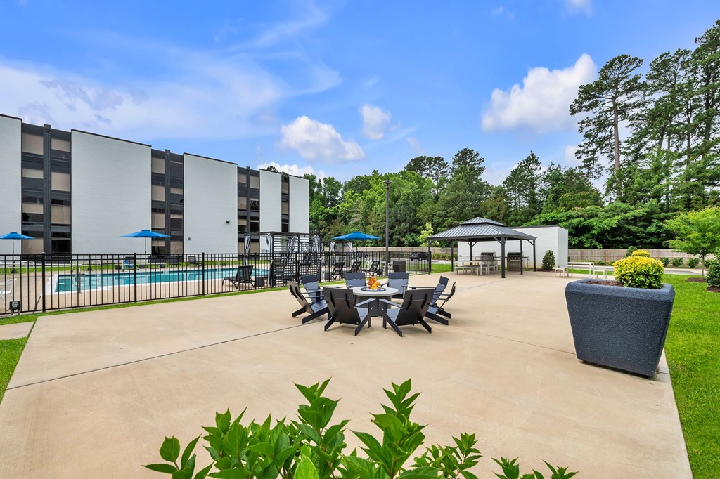 A large outdoor patio area with a table set for dining and a pool in the background.