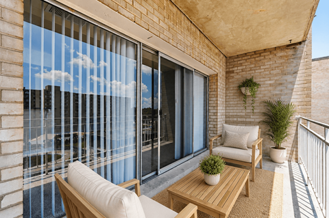 A balcony with a table and chairs overlooking a cityscape.