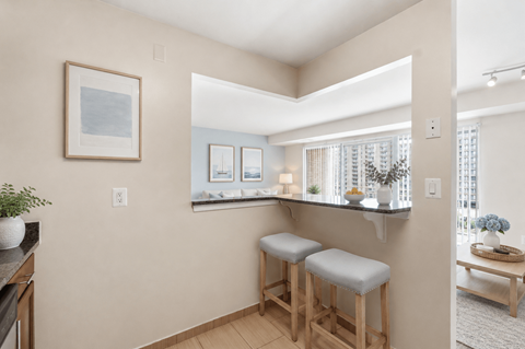 A kitchen with a bar stool and a framed picture on the wall.