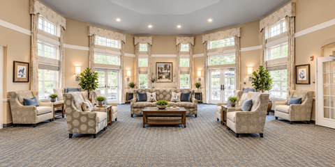 A spacious living room with a carpeted floor and large windows.