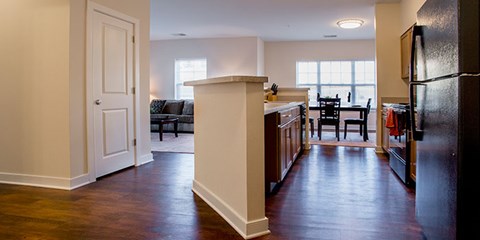 A kitchen with a black refrigerator and wooden floors.