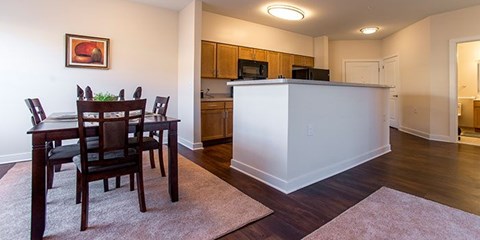 A dining room with a white island and wooden chairs.