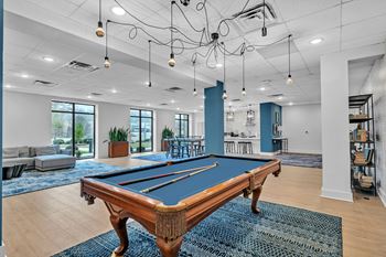 A pool table is in the middle of a room with a blue rug.