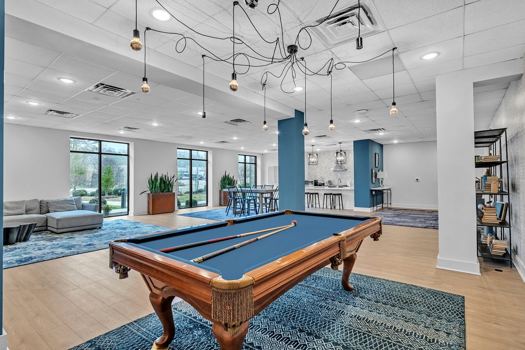 A pool table is in the middle of a room with a blue rug.