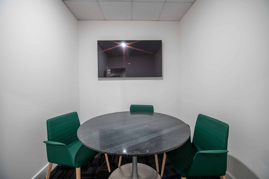 A conference room with a table and four chairs.