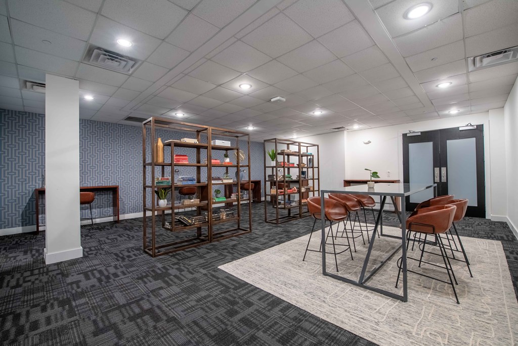 A room with a table surrounded by chairs and a bookshelf.