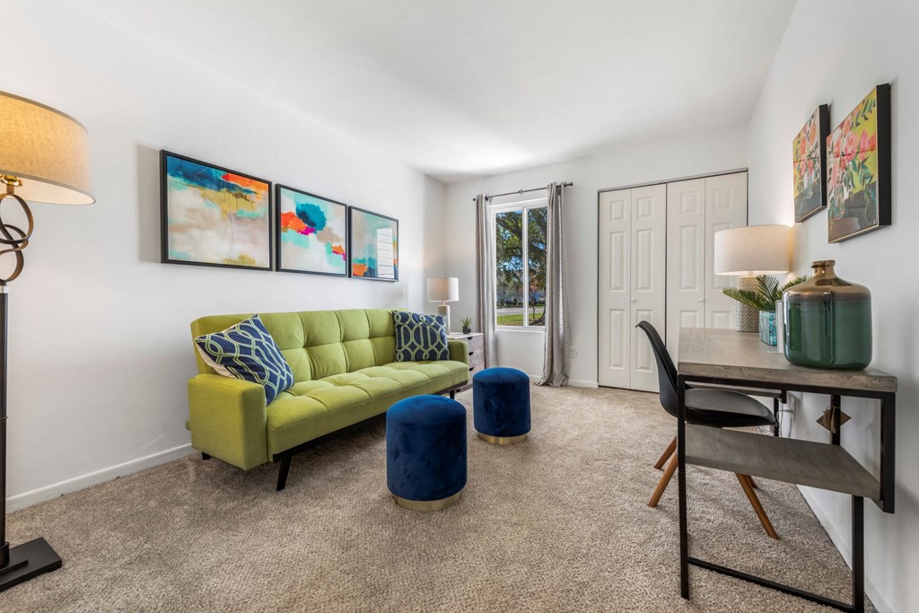 a living room with a yellow couch and a desk with a chair