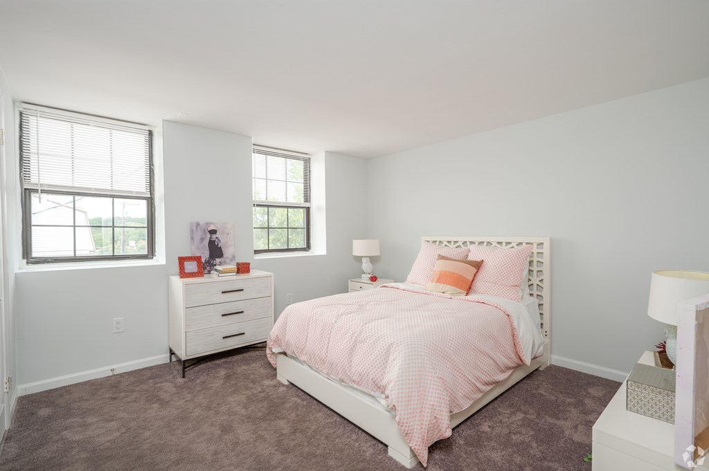 A bedroom with a bed, nightstand, and window.