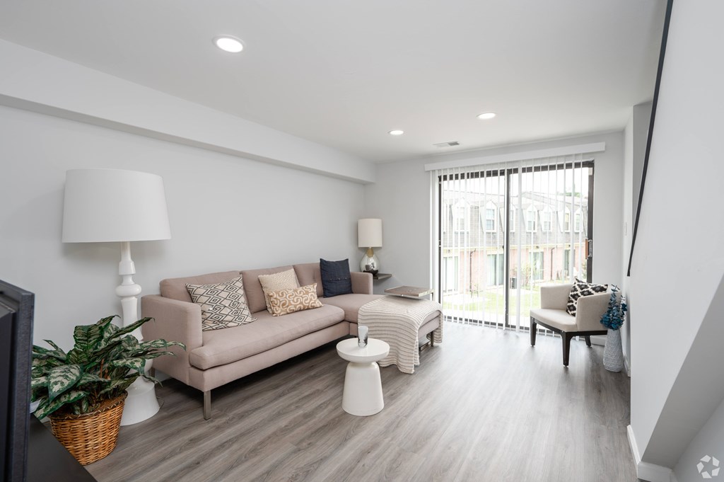 A living room with a couch, chair, and potted plant.
