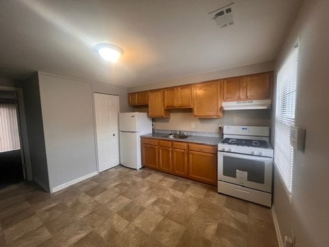 A kitchen with wooden cabinets and a tiled floor at Pleasantview Apartments, Baltimore, MD