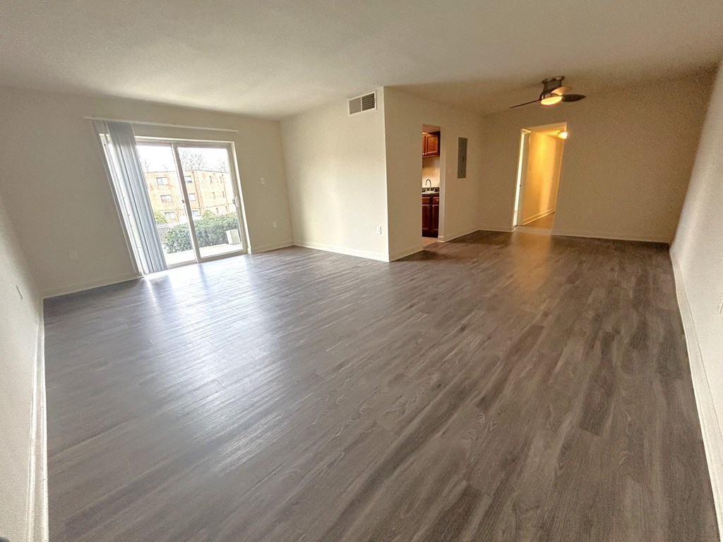 LVP  Flooring- an empty living room with wooden floors and a sliding glass door