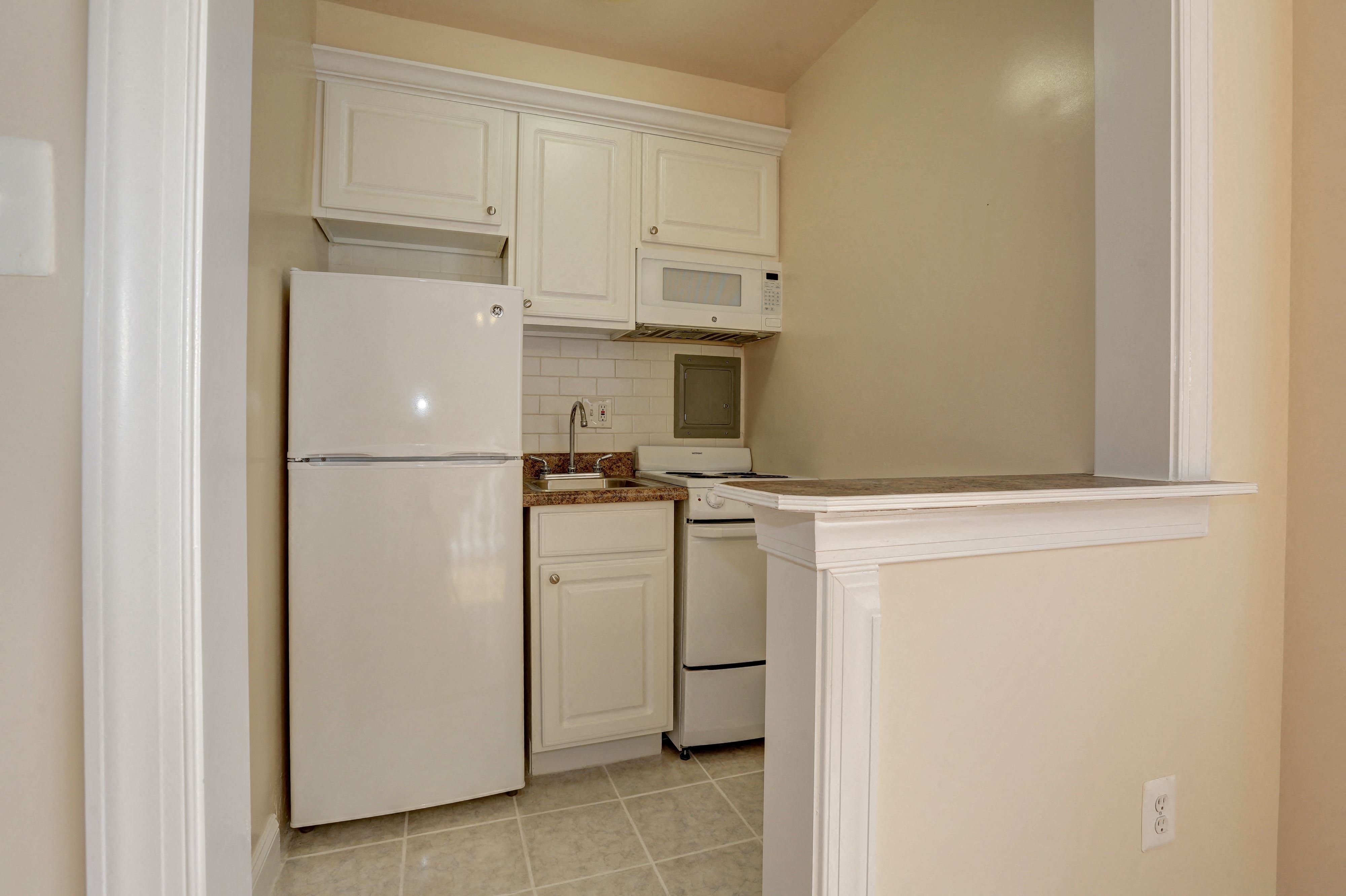 a kitchen with white cabinets and a white refrigerator