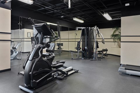 A gym with a variety of equipment including treadmills, weights, and exercise machines.