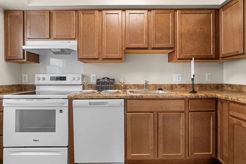 A kitchen with brown cabinets and white appliances.