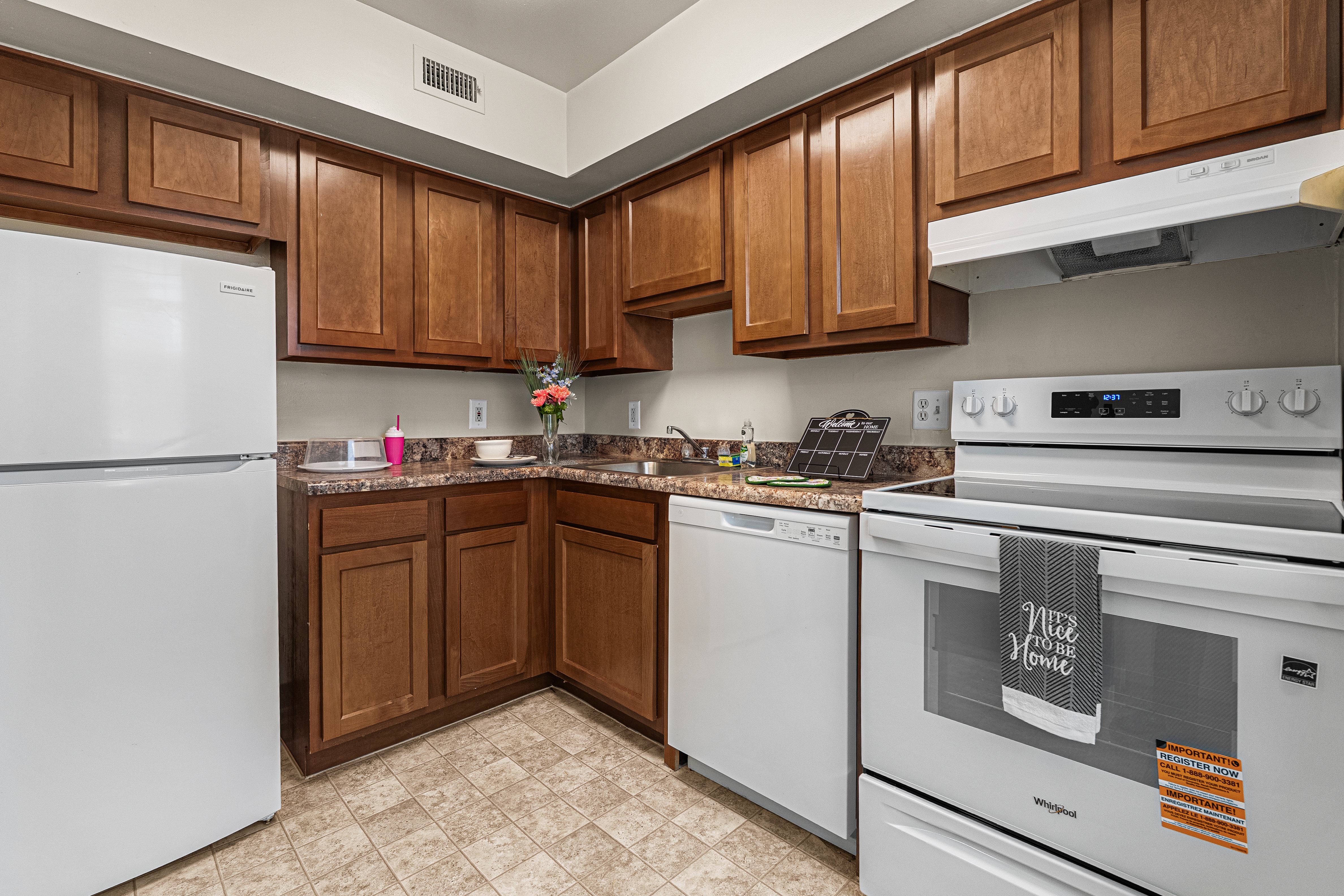 A kitchen with white appliances and brown cabinets.