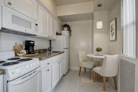 A kitchen with white appliances and a table with two chairs.