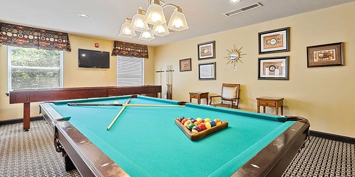 A pool table with a green cloth and a wooden cue stick. at Rainier Manor Apartments, Mount Rainier, MD, 20712