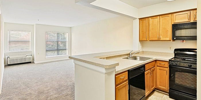 A kitchen with black appliances and wooden cabinets at Rainier Manor Apartments, Mount Rainier, MD