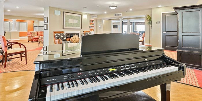 A black piano sits in a living room with a red carpet at Rainier Manor Apartments, Maryland, 20712