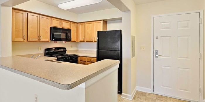 A kitchen with black appliances and wooden cabinets at Rainier Manor Apartments, Mount Rainier, Maryland