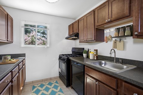 a kitchen with wooden cabinets and black appliances and a sink