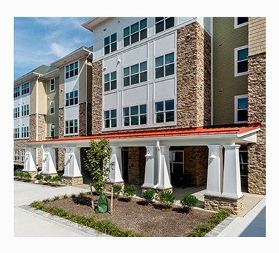 A building with a red roof and white columns. at Rainier Manor Apartments, Mount Rainier, MD