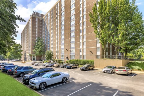 A parking lot with cars and a tall building in the background at Ashton Heights Apartments, Suitland, MD