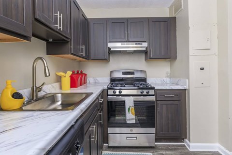 A modern kitchen with dark wood cabinets and stainless steel appliances.