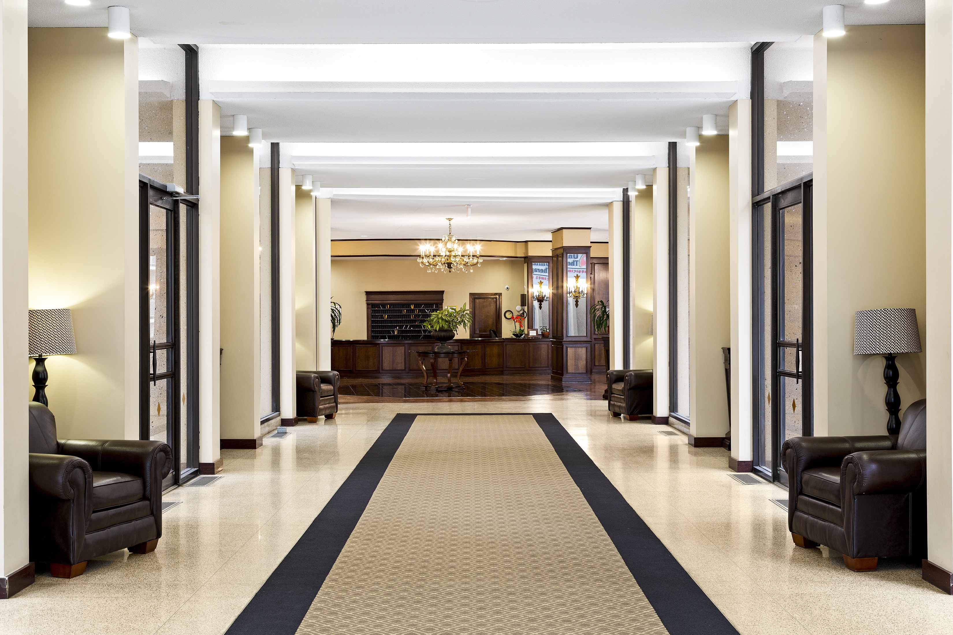 A long hallway with a black and white carpet and black furniture on either side.