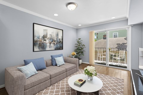 A living room with a grey couch, a white coffee table, and a painting on the wall.
