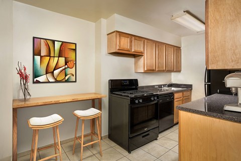 a kitchen with black appliances and a counter with two stools