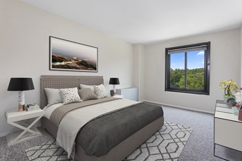 bedroom with gray bedding, nightstand and large windows at remington place apartments in fort washington, MD - Photo Gallery 5