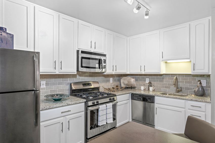 kitchen at Versailles Apartments in Towson, MD with stainless steel appliances, white cabinets and stone countertops - Photo Gallery 1