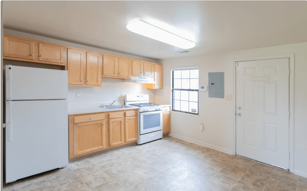 A kitchen with wooden cabinets and a white refrigerator. A kitchen with wooden cabinets and a white refrigerator at Dutch Village Apartments, Baltimore, 21234