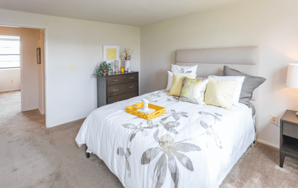 A bedroom with a large bed and a nightstand with a lamp at Dutch Village Apartments, Baltimore