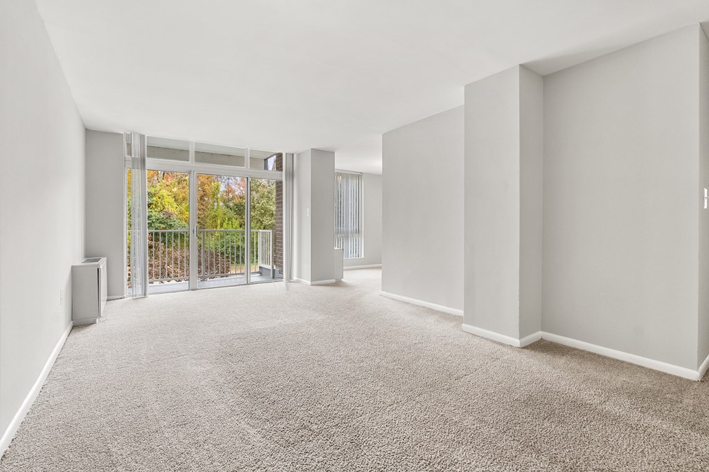 A spacious room with a carpeted floor and sliding glass doors leading to a garden.