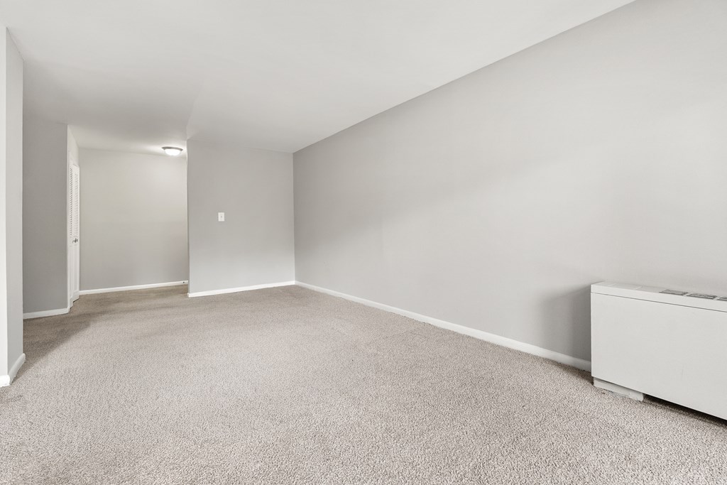 A room with a carpeted floor and a white radiator.