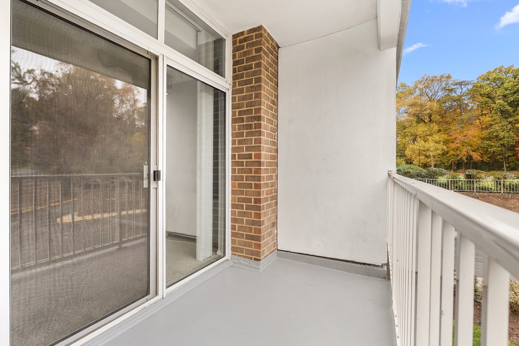A balcony with a glass door and a brick pillar.