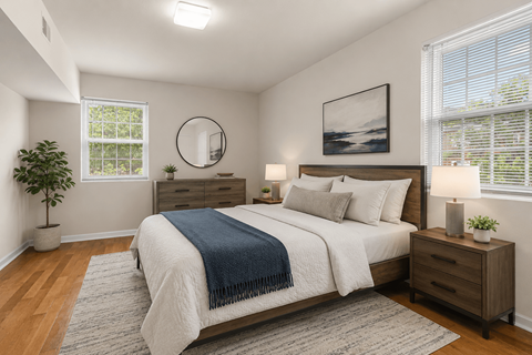 A bedroom with a large bed, a plant, and a framed picture on the wall.