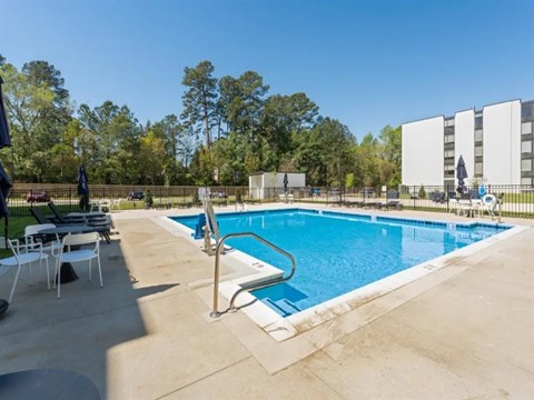 a swimming pool at a hotel with tables and chairs at The James On Merrimac, Williamsburg, VA