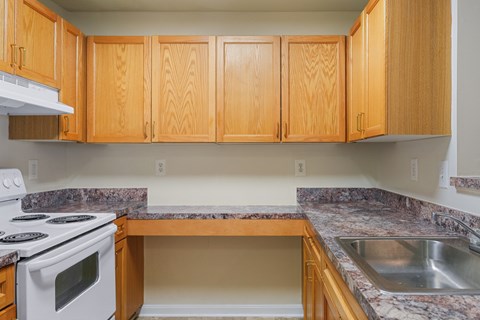A kitchen with wooden cabinets and a white stove top oven.