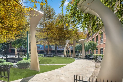 A park with a sculpture of a tree branch and a pathway.