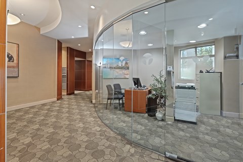 A glass wall separates the office from the kitchen area.