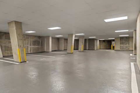 A spacious parking garage with concrete pillars and a grey floor.